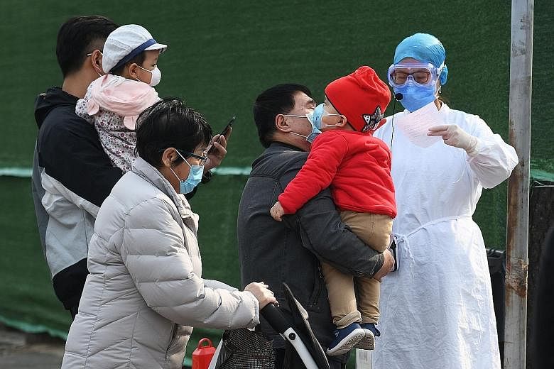 Families being screened by a hospital staff member while waiting to enter a children's hospital in Beijing in March, amid the coronavirus pandemic. In Singapore, Covid-19 has infected 57 children - those aged 16 and younger - but none has had to be i