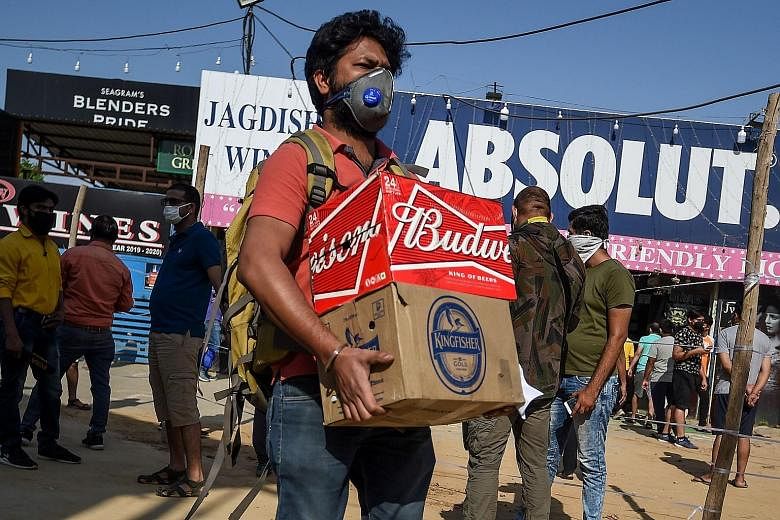 A man with boxes of alcohol outside a liquor shop yesterday in Gurgaon, India, after restrictions were eased. People can leave their homes between 7am and 7pm and shops can reopen, but international and domestic flights remain suspended, along with c