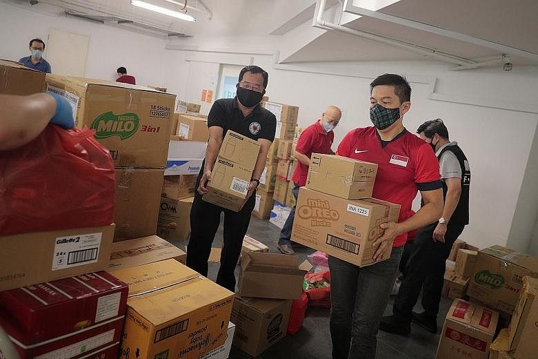 Speaker of Parliament Tan Chuan-Jin, Migrant Workers' Centre chairman Yeo Guat Kwang (in black vest behind him) and Singapore Kindness Movement general secretary William Wan (background, in red) helping with care packs for migrant workers at the Bibl