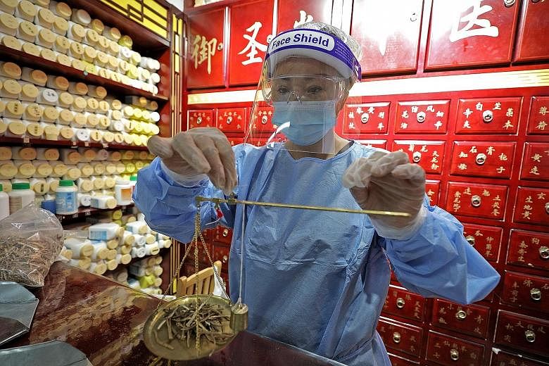 Physician Li Huarong preparing Chinese herbs for her patients on Tuesday, the first day that 130 medical halls attached to registered TCM practitioners could resume treatments and services since the start of circuit breaker measures.