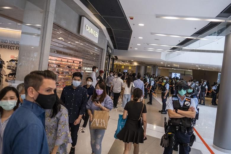 Shoppers walking past police officers standing guard during a protest at the International Finance Centre mall in Hong Kong's Central district yesterday, as the government eased social distancing rules.