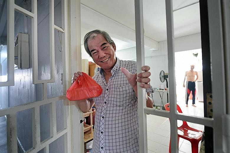 Mr Lim Chin Kiat, 74, with a packet of food he had just received from volunteers Joel Tan, 44, and Gracia Yap, 45, at his Ang Mo Kio Avenue 4 rental flat yesterday. ST PHOTO: ALPHONSUS CHERN