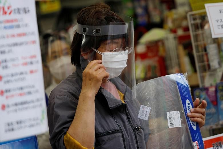 A customer with a protective face shield at a Tokyo retail store yesterday amid an ongoing state of emergency in Japan.