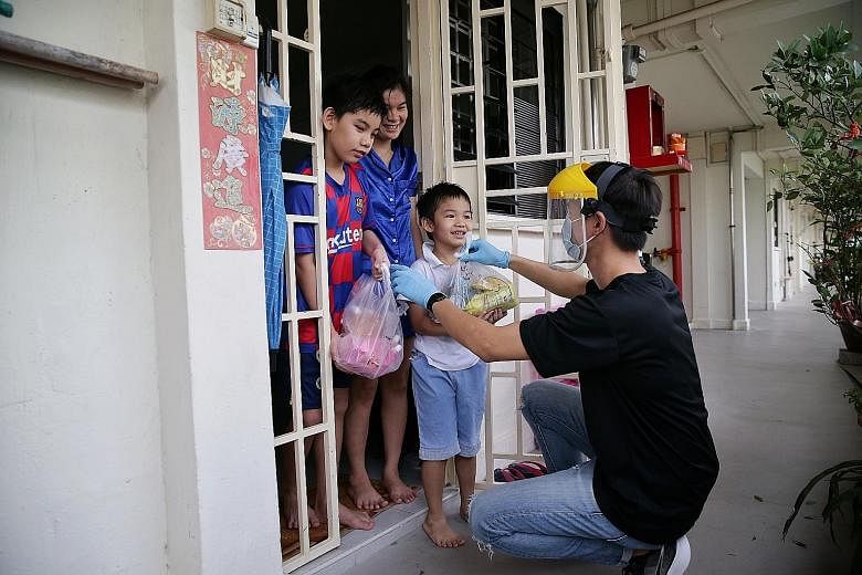 Housewife Kellyn Ruan, 36, and her sons Jackson Low, 11, and Johnson Low, six, receiving packs of Mr Bean products like fresh soya milk pouches yesterday from FutuReady Asia's Character & Leadership Academy staff member Nick Chan, 22.
