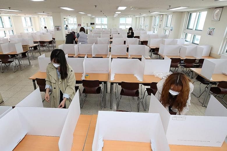 Teachers setting up dividers on tables in a cafeteria at the Duksoo High School in Seoul yesterday to get the school ready for reopening next Wednesday. Incheon city is on high alert for mass infections, after a 25-year-old teacher and resident was f