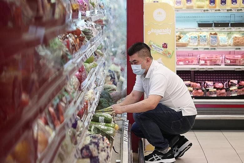 Mr Alex Yeo, a sous-chef at Jiang-Nan Chun at Four Seasons Hotel Singapore, stocking shelves at Cold Storage at The Rail Mall. He is among more than 150 staff from seven hotels who have been redeployed to stores under the Dairy Farm Group. ST PHOTO: 
