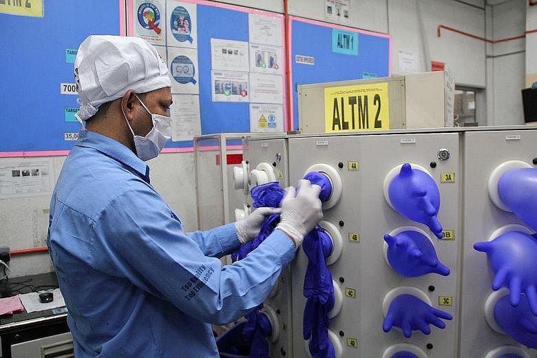 A worker inspecting gloves at Top Glove's factory in Klang, Malaysia. The company is among those that have seen their stock prices surge this year, backed by the spike in demand for medical supplies. Globally and in Singapore, investors are focusing 