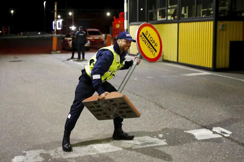 An Estonian border police officer removing a stop sign at the Ikla crossing point at midnight yesterday.