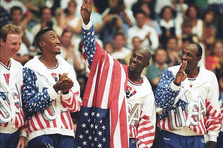 American basketball player Michael Jordan (draped with flag) flashes a victory sign as he stands with teammates (from left) Larry Bird, Scottie Pippen and Clyde Drexler. They were nicknamed the Dream Team after winning the Olympic gold in Barcelona, Spain