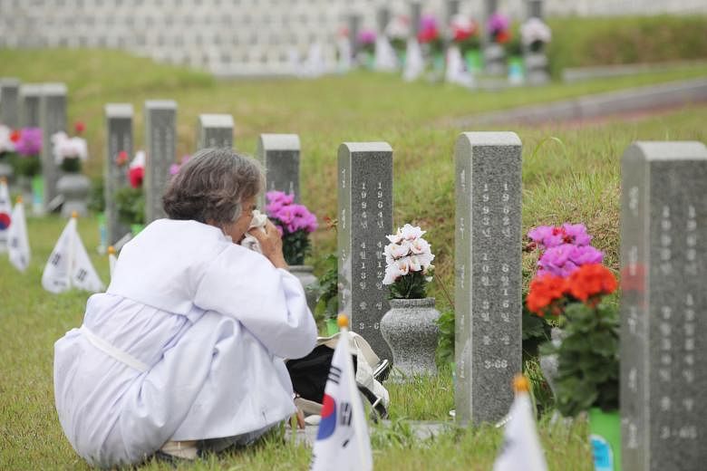 A woman crying near a grave at a national cemetery honouring those killed in the 1980 Gwangju democracy uprising in Gwangju, South Korea, yesterday. The official death toll is around 160 - including some soldiers and police - and more than 70 missing