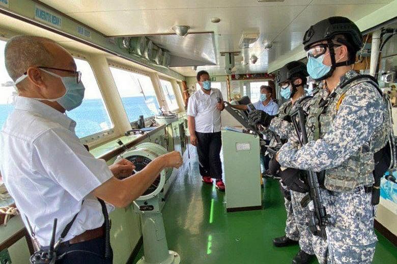 Above: Private Nigel Lim (left), 22, putting on personal protective equipment that includes a mask, goggles and latex gloves. Left: An Accompanying Sea Security Team operator speaking to a crew member on board a merchant ship during a recent operatio