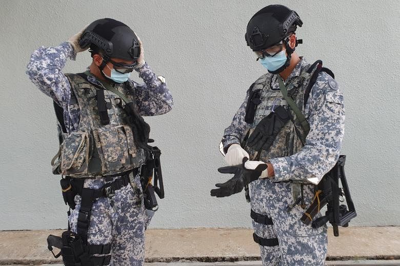Above: Private Nigel Lim (left), 22, putting on personal protective equipment that includes a mask, goggles and latex gloves. Left: An Accompanying Sea Security Team operator speaking to a crew member on board a merchant ship during a recent operatio