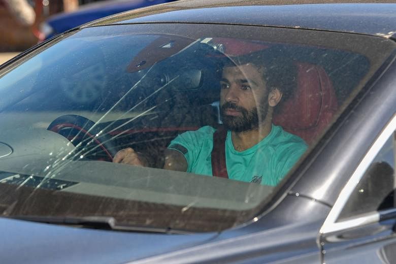 Above: Tottenham Hotspur staff members wearing masks at the entrance to the team's training complex in North London. Left: Liverpool forward Mohamed Salah arriving at the club's training ground in Melwood yesterday to resume training ahead of the lea