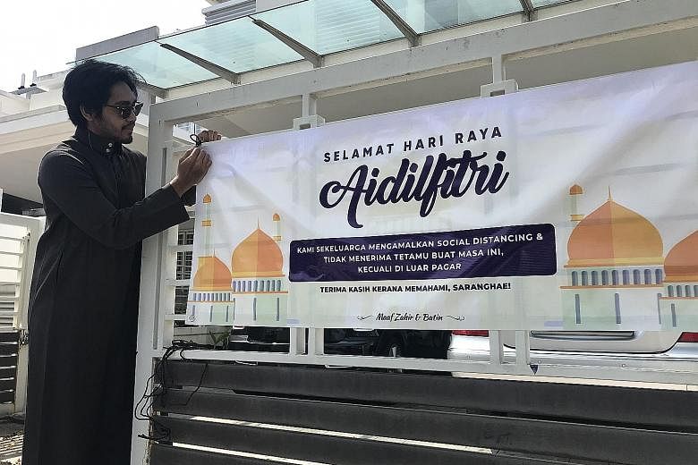 Mr Ahmad Afif Zainol putting up a Hari Raya banner outside his home in Alam Impian, Selangor. It comes with the message that the family is not accepting visitors amid the coronavirus pandemic.
