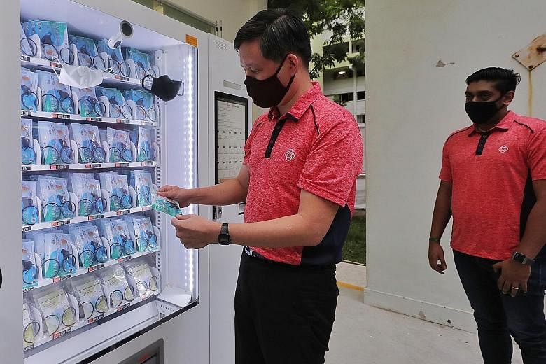 Trade and Industry Minister Chan Chun Sing holding a mask from a vending machine at Pek Kio Community Centre yesterday. About 400 of these machines will be placed at all community clubs for those who are unable to pick up their free masks from collec