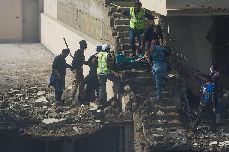Above: An injured victim being evacuated by rescue workers from the site in a Karachi neighbourhood after a Pakistan International Airlines aircraft crashed into homes while on approach to the city's airport yesterday. There were no estimates of casu
