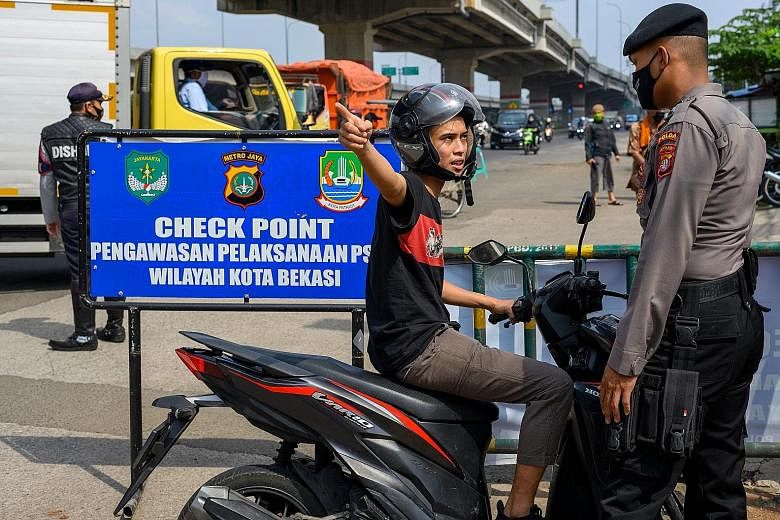 An Indonesian official questioning a motorist leaving Jakarta at a checkpoint on Friday. The government has urged people not to travel back to their home towns for Eid al-Fitr celebrations amid concerns over the coronavirus outbreak. The numbers of C