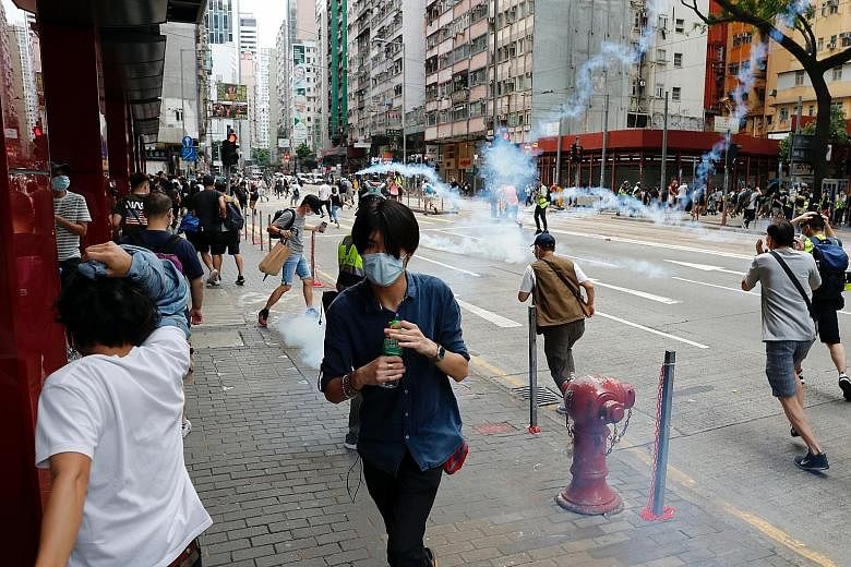 Anti-government protesters reacting as riot police fired tear gas to disperse them during a march against Beijing's plans to impose national security legislation in Hong Kong yesterday. At least 180 people were arrested and the Hospital Authority sai