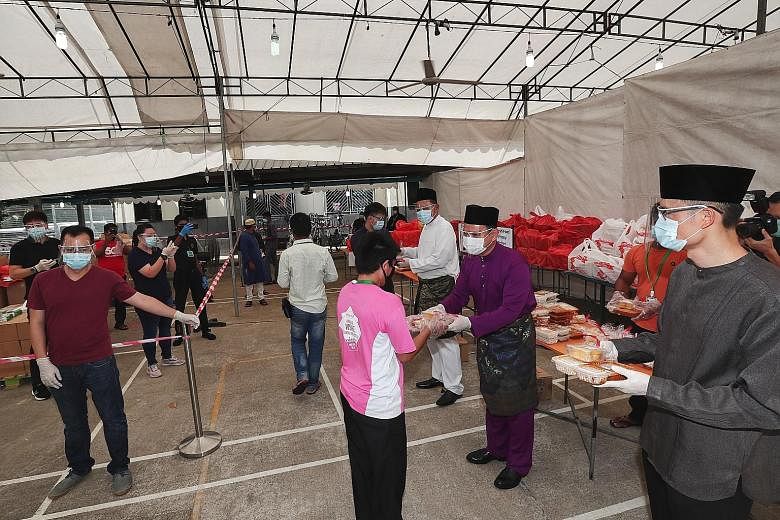 Minister of State for Manpower Zaqy Mohamad (centre), flanked by Muis chief executive Esa Masood (right) and SMCCI deputy president Abu Bakar Mohd Nor, distributing special meals and festive goodies to migrant workers at Woodlands Dormitory to mark H