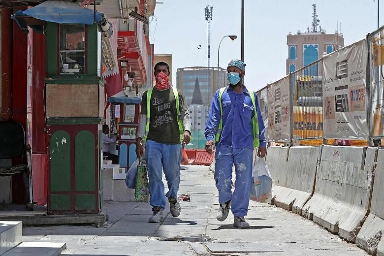 Workers wearing protective masks on a street in Doha, Qatar, on May 17. Like in Singapore, the outbreak in Qatar has centred on its foreign workers, who outnumber Qataris in the workforce by nearly 20 to one. Qatar's ambition to host the World Cup ha