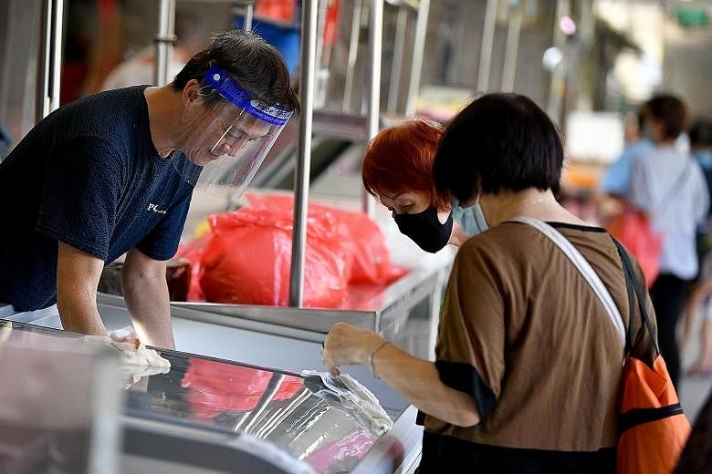 A stall owner wearing a face shield while serving customers at Tiong Bahru Market. Experts say that when wearing a face shield, make sure your whole face is covered, from ear to ear and forehead to chin. There should be no gaps between the securing h