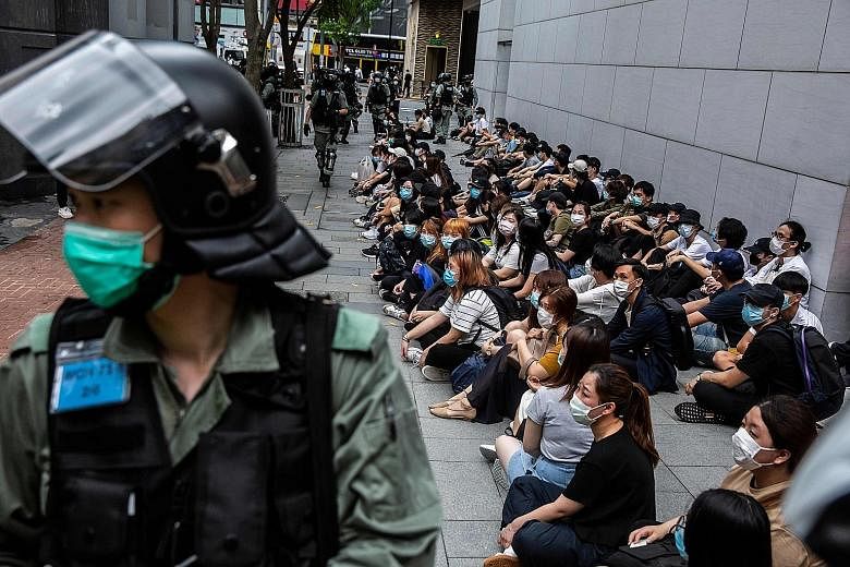 Riot police detained a group of people during a protest in the Causeway Bay district of Hong Kong yesterday, as the city's legislature debated over a law that would criminalise disrespect of the national anthem. Small groups of protesters stayed on t