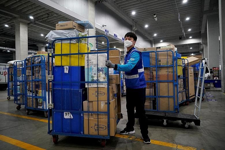 A delivery man for Coupang loading packages to deliver them in Incheon, South Korea, on March 3. So far, at least 36 cases have reportedly been linked to an outbreak at the logistics centre in Bucheon, west of Seoul. PHOTO: REUTERS