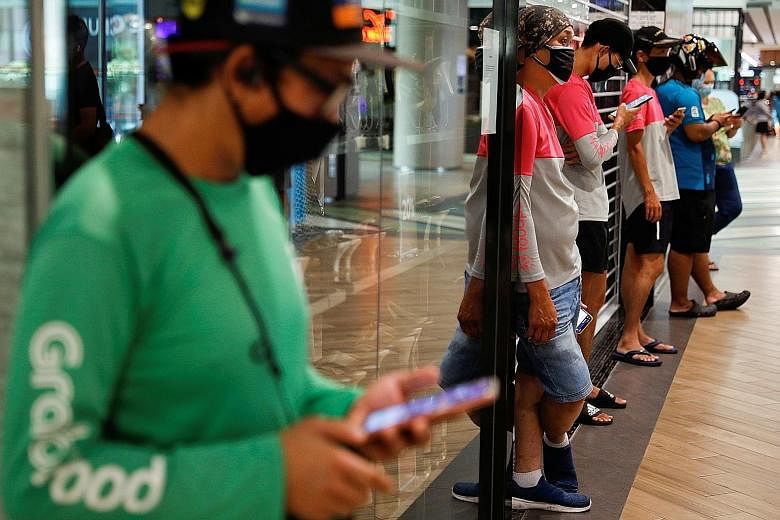 Food-delivery riders queueing up to pick up their orders at a shopping mall on Tuesday. People eligible for the Self-Employed Person Income Relief Scheme will receive three quarterly payouts of $3,000 each, with the next two payments in July and Octo