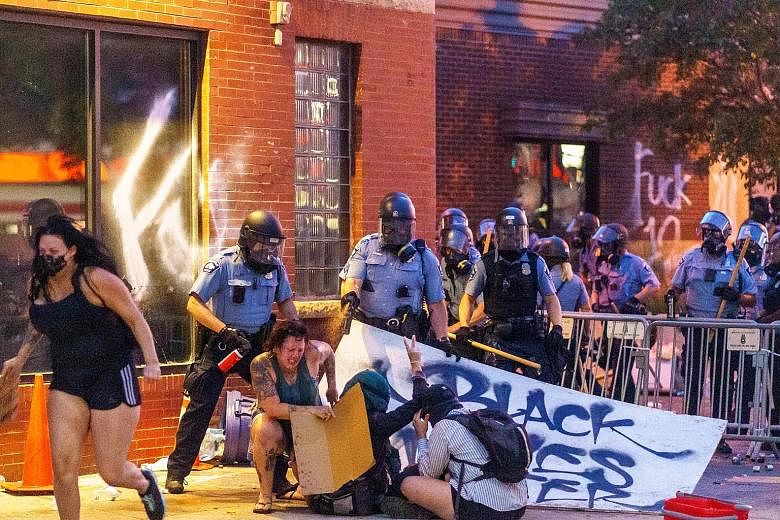 Police removing barricades set up by protesters outside the Third Police Precinct in Minneapolis on Wednesday. Left: Police in Minneapolis using pepper spray on protesters during a demonstration outside the Third Police Precinct on Wednesday over the