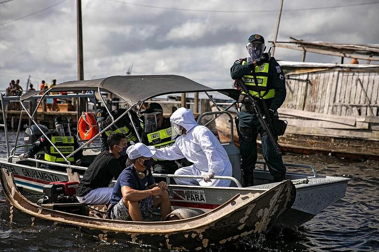 A government medical worker, in a joint operation with military police, checking the temperature of a passenger on a boat in Brazil's Para state earlier this week. Most state governments in the country have stuck to the World Health Organisation's gu