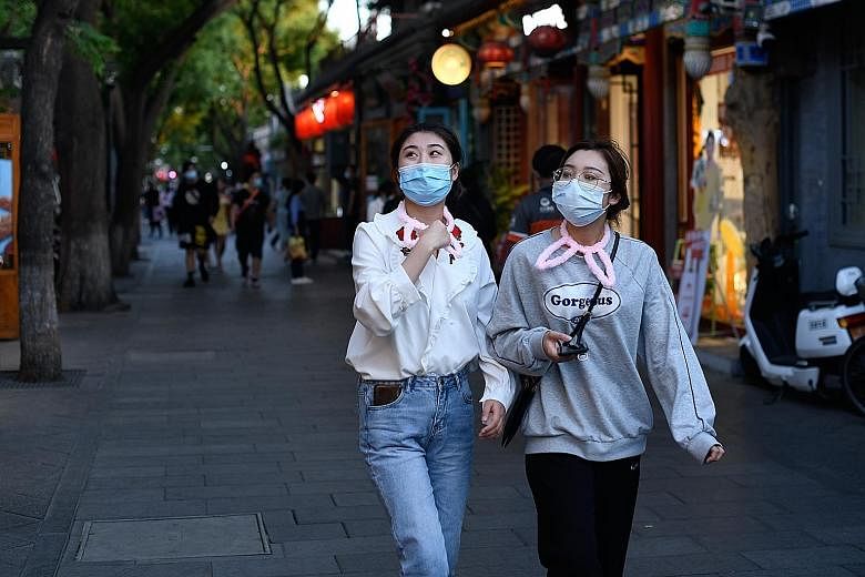 Women in masks visiting a Beijing shopping alley on Wednesday. Premier Li Keqiang said 70 per cent of the funds in the stimulus package he unveiled last week will go directly to supporting small and medium-sized enterprises, and spur consumption.