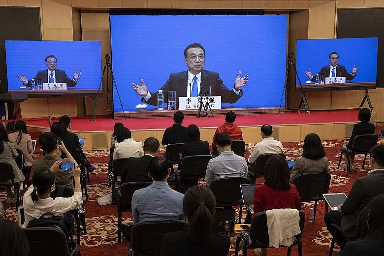Chinese Premier Li Keqiang seen speaking on screens during his remote video-streamed press conference marking the end of the third plenary session of the 13th National People's Congress in Beijing yesterday. PHOTO: EPA-EFE