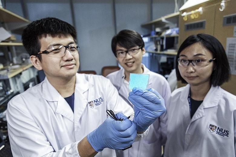 Assistant Professor Benjamin Tee (centre), who leads the NUS research team that is behind the supermaterial, with two team members - doctoral student Wang Guanxiang, who is holding up a sample of the new material, and research fellow Tan Yu Jun.