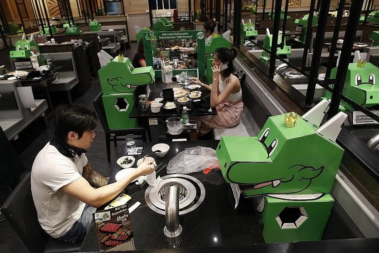 Over in Bangkok, Thailand, cardboard dragons shaped after Bar-B-Q Plaza restaurant’s mascot watch on as diners tuck into their food. Thailand has lifted some of its coronavirus restrictions, but safe distancing is still required, especially in restaurants