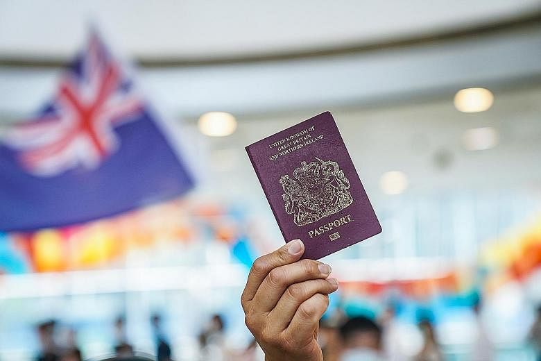 A British national (overseas) passport held aloft as a colonial-era Hong Kong flag was waved during a rally in the city on Friday. Three million residents could soon have the theoretical right to settle in Britain. PHOTO: BLOOMBERG