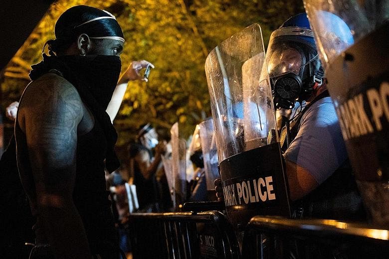 Above: US police in riot gear facing off against protesters across from the White House in Washington last Saturday, during a demonstration over the death of Mr George Floyd, an unarmed black man, who died after a white Minneapolis police officer kne