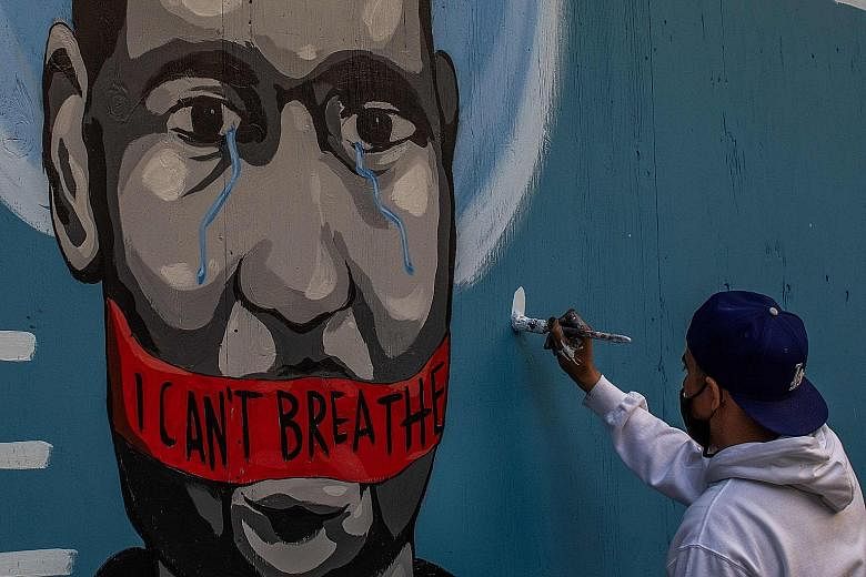 An artist named Celos painting a mural in Los Angeles last Saturday in protest against the death of Mr George Floyd.