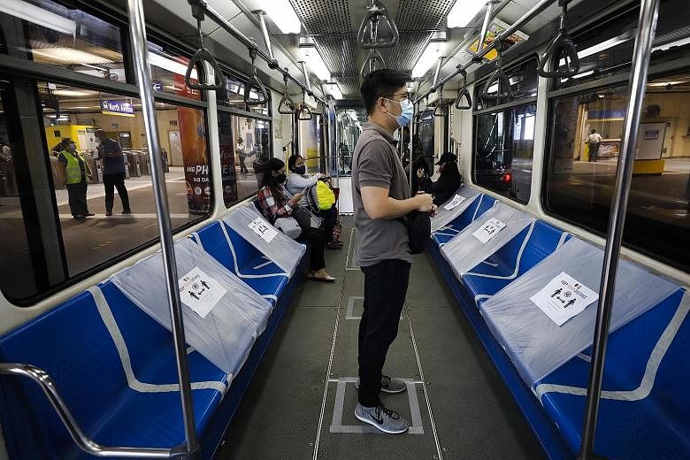 A train passenger in Quezon City, Manila, yesterday. The Metro Rail Transit covered half its train seats with plastic so that those seated would be spaced at least 1m apart, resulting in long queues at stations.