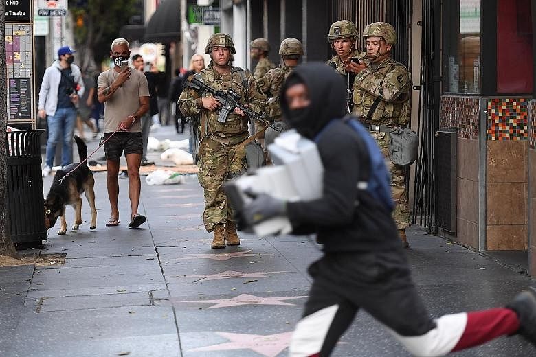 A looter running past National Guard personnel in Hollywood, California, on Monday. The protesters have comprised not just African Americans but to a large extent white people and also, by and large, young people. They have been mostly peaceful durin