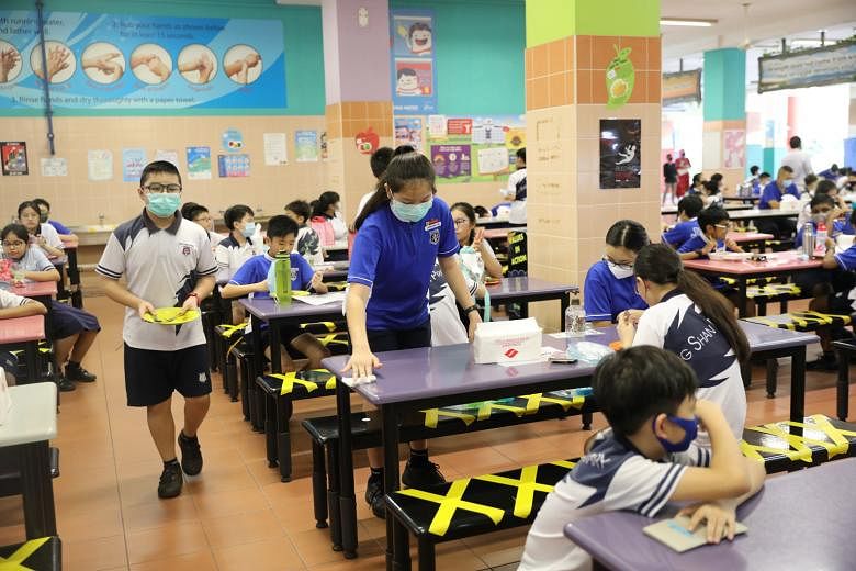 Primary 6 pupil Japhanie Tan of Jing Shan Primary School wiping down the table in the canteen after finishing her lunch yesterday. Despite restrictions such as having to wear face masks throughout the day, not talking to friends without masks on and 
