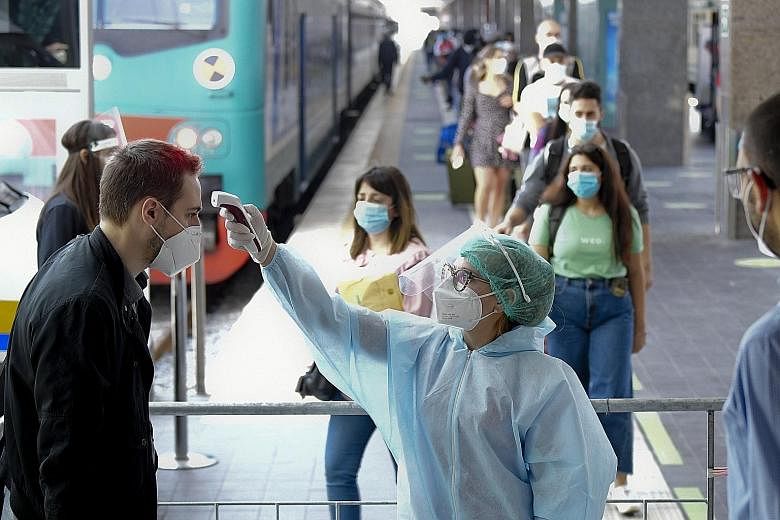 A passenger having his temperature checked before entering Naples Central Station. International flights into Milan, Rome and Naples have increased, with a few also arriving at smaller, regional airports. But there were concerns that those who usuall