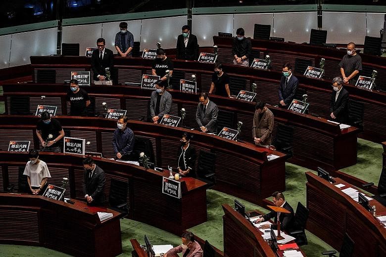 Pro-democracy legislators standing in silence before walking out of the chamber in Hong Kong yesterday, ahead of a vote on a law banning insults to China's national anthem. Lawmakers approved the Bill with 41 in favour and one against, but the 75-sea