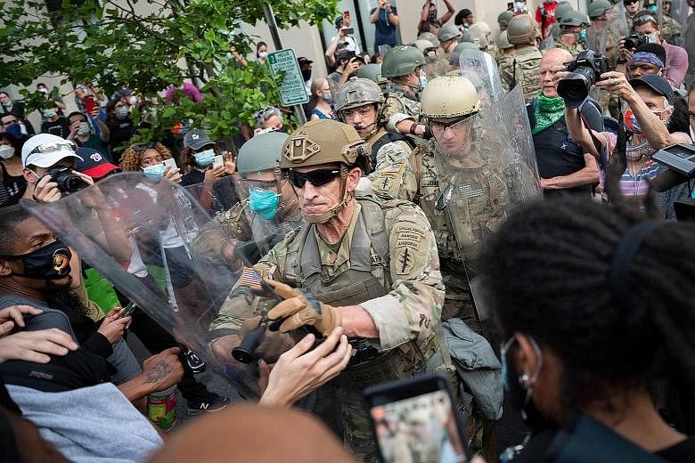 Protesters scuffling with US Army soldiers near the White House in Washington, DC on Wednesday. The unrest, however, was far less destructive on Tuesday and Wednesday than during the previous few days. Above: A crowd protesting in San Francisco, Cali