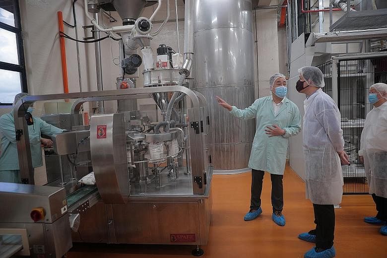 Prima Limited deputy plant manager Steve Ang describing the packing process to Trade and Industry Minister Chan Chun Sing (second from right), with Prima chairman and group CEO Primus Cheng (right) looking on, at the company's flour mill in Keppel Ro