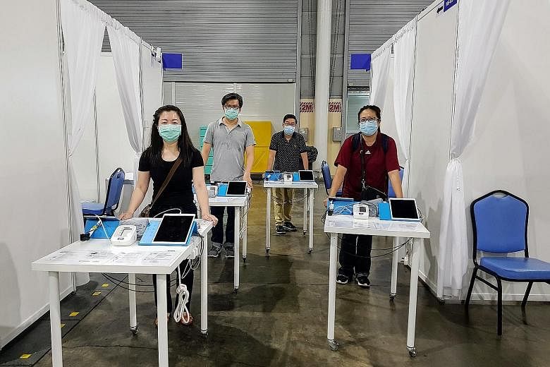 Integrated Health Information Systems staff with the mobile kiosks at Singapore Expo. The kiosks allow patients to take their own vital signs readings. PHOTO: IHIS