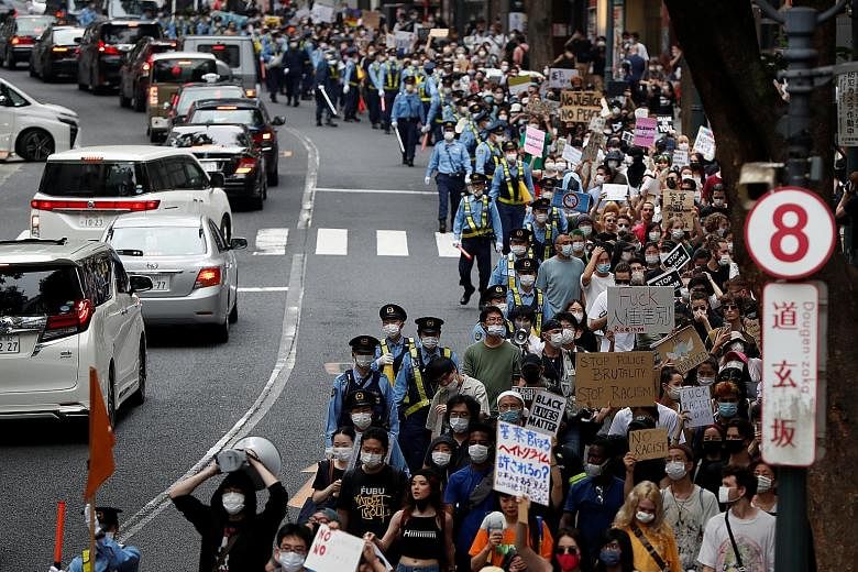 People holding placards during a protest march in Tokyo yesterday over the alleged police abuse of a foreign man, in echoes of various Black Lives Matter demonstrations across the world. PHOTO: REUTERS