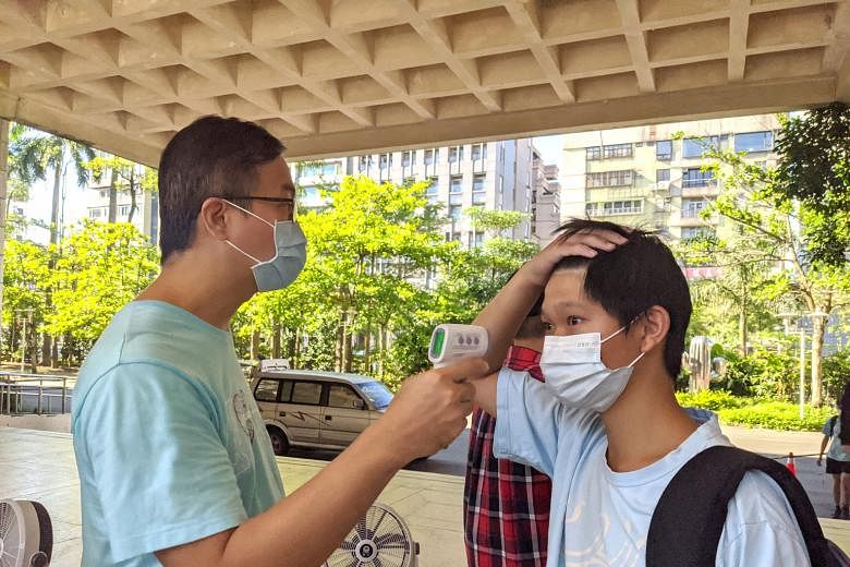 A student at the Affiliated Senior High School of National Taiwan Normal University in Taipei having his temperature taken. ST PHOTO: KATHERINE WEI Pupils at Kyung Hee Elementary School in Seoul have to sanitise their hands before proceeding to their
