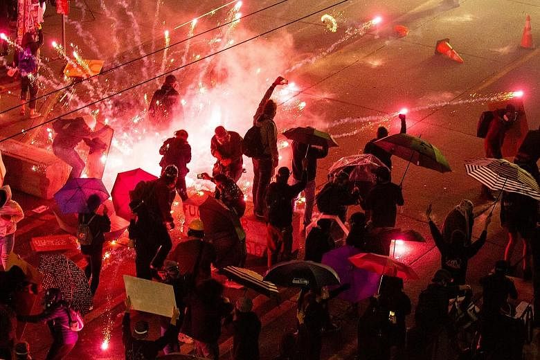Above: Demonstrators clashing with police near the Seattle Police Department's East Precinct on Sunday, in Seattle, Washington state. The protests have deepened a political crisis for United States President Donald Trump, who repeatedly threatened to