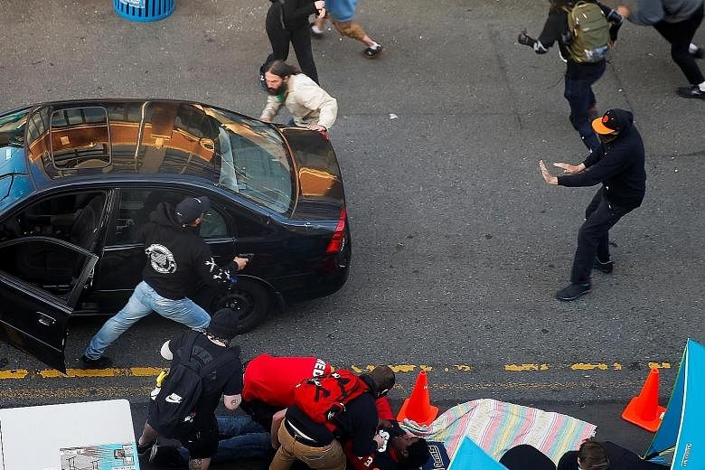 The gunman exiting a car as his victim is tended to by medics in Seattle, Washington, on Sunday. A local television station said the victim, a protester, had been shot in the arm after he approached the gunman when he was still inside the car. The ar