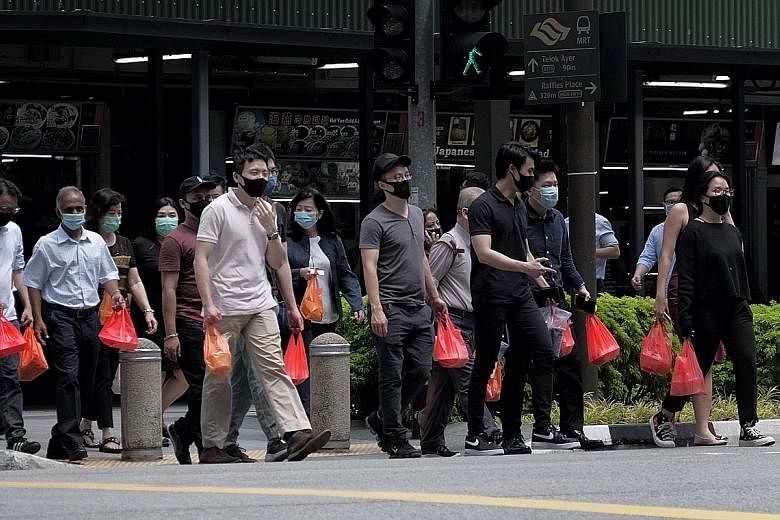 Office workers exiting the Market Street Interim Hawker Centre with their packed lunches yesterday. The daily average for new community cases has increased to nine in the past week from three the week before. ST PHOTO: GAVIN FOO